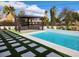 Inviting pool area featuring a modern pergola, stylish tiling, and a unique grass-and-stone walkway at 8780 Haven St, Las Vegas, NV 89123