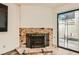 Cozy living room with brick fireplace, glass sliding door, and wood-look flooring at 5701 Pearldrop Ave, Las Vegas, NV 89107