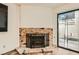 Cozy living room features laminate flooring, a brick fireplace, and sliding glass doors to the patio at 5701 Pearldrop Ave, Las Vegas, NV 89107