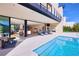Stunning outdoor living space with a modern pool, lounge chairs, and seamless transition to the indoor dining and living areas at 4915 Summit Overlook Dr, Las Vegas, NV 89135