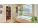 Bright bathroom features a jacuzzi tub, glass block window, and walk-in closet at 10909 Bramante Dr, Las Vegas, NV 89141