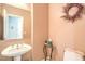 Cozy powder room with pedestal sink, decorative mirror, and half bath at 10909 Bramante Dr, Las Vegas, NV 89141