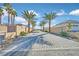 Paver driveway lined with palm trees and desert landscaping leads to this stunning property at 6615 Whispering Sands Dr, Las Vegas, NV 89131
