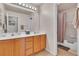 Bathroom with double sinks, wooden cabinets, a well-lit mirror and a shower with a curtain at 10105 Shore Pine Ave, Las Vegas, NV 89129