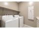 Efficient laundry room equipped with a washer, dryer, and convenient shelving for storage at 1438 Dire Wolf Ave, North Las Vegas, NV 89084