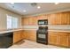 Modern kitchen with light wood cabinets and black appliances at 4750 Newby Hall Ct, Las Vegas, NV 89130