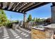 Outdoor kitchen with stone counters, stainless steel appliances, and a pergola at 10590 Dryades Ave, Las Vegas, NV 89166