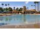 Inviting community pool and recreation area with palm trees, turquoise umbrellas, and sandy beach area at 3125 N Buffalo Dr # 1089, Las Vegas, NV 89128
