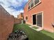 Private backyard area with artificial turf, a brick wall, and a sliding door leading inside at 7961 Alta Lima Valley Ct, Las Vegas, NV 89178