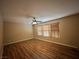 Spacious bedroom featuring wood-look floors, ceiling fan, and natural light from three large windows at 7961 Alta Lima Valley Ct, Las Vegas, NV 89178