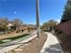 Neighborhood walking path with desert landscaping, green grass, and concrete sidewalk, offering a scenic stroll at 7961 Alta Lima Valley Ct, Las Vegas, NV 89178