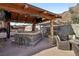 Outdoor kitchen features a stone bar, pizza oven, BBQ and seating under a wood pergola, ideal for gatherings at 868 Marina Dr, Boulder City, NV 89005