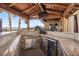 Outdoor kitchen with stone counters, sink, mini-fridge and mountain view making this the perfect outdoor entertaining area at 868 Marina Dr, Boulder City, NV 89005