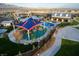 An aerial view showcases the community's playground, pool, gym, and clubhouse nestled between lush landscapes at 10208 Bismarck Palms Ave, Las Vegas, NV 89166