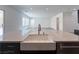 View of a white quartz kitchen island featuring a farmhouse sink and black wood cabinets at 10208 Bismarck Palms Ave, Las Vegas, NV 89166