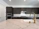 Close up shot of a white quartz kitchen island and sink with black wood cabinets at 10208 Bismarck Palms Ave, Las Vegas, NV 89166