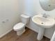 Clean bathroom with pedestal sink, toilet, and wood-look tile floor at 1029 Ferodale Ave, North Las Vegas, NV 89084