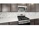 Stylish kitchen featuring stainless steel gas range and marble backsplash that complements the dark cabinetry at 655 N Water St, Henderson, NV 89015