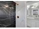 Modern bathroom with black marble shower, white marble walls, and double sinks with brass fixtures at 6315 N El Capitan Way, Las Vegas, NV 89149