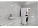 Modern bathroom featuring a sleek white vanity with a vessel sink, washer and dryer, and marble tile at 6315 N El Capitan Way, Las Vegas, NV 89149