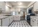 Galley kitchen featuring white cabinetry, tile countertops, and black and white tile flooring at 3125 Pinehurst Dr # A, Las Vegas, NV 89109