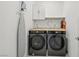 Functional laundry room with modern machines, a utility sink, and storage space at 10172 Magnolia Creek St, Las Vegas, NV 89141