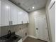 Bright laundry room with white cabinets, quartz countertops, and a utility sink at 3060 Spy Glass Ave, Pahrump, NV 89048