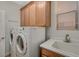 Laundry room with front loading washer and dryer, utility sink, and built-in cabinets at 7943 Sleeping Lily Dr, Las Vegas, NV 89178