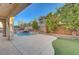 Relaxing pool area with palm trees, rock waterfall, and covered patio at 7943 Sleeping Lily Dr, Las Vegas, NV 89178