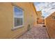 A brick-paved backyard with tan stucco walls, a small window, and string lights along the brick fence at 1065 Admiral Emblem St, Henderson, NV 89015