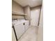 Bright laundry room features a white washer and dryer, floating shelf and white wood-look tile flooring at 2678 Aracatuba Ave, Las Vegas, NV 89121