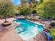 Large pool and jacuzzi area with stone features and surrounding greenery create a private backyard oasis at 3841 Hildebrand Ln, Las Vegas, NV 89121