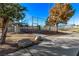 Fenced tennis court with trees in the background, accessible via a concrete walkway, offers a recreational amenity at 2368 Winterwood Blvd, Las Vegas, NV 89142