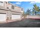 Tan three-story townhome with two-car garage and a red curb at 2410 Encouraging Ct, Henderson, NV 89052