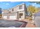 Tan three-story townhome with two-car garage, landscaping, and a red curb at 2410 Encouraging Ct, Henderson, NV 89052