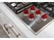 Close up on a Wolf cooktop with red knobs, marble countertops and bronze fixtures at 605 Canyon Greens Dr, Las Vegas, NV 89144