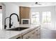 Elegant kitchen featuring a marble countertop island, black faucet, and view of living space with fireplace at 605 Canyon Greens Dr, Las Vegas, NV 89144
