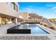 Modern infinity pool with spa and lounge chairs, set against a landscaped backyard and hilltop at 612 Dragon Mountain Ct, Henderson, NV 89012