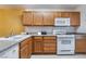 Well-lit kitchen featuring wood cabinets, white appliances, and speckled granite countertops at 10332 Perfect Parsley St, Las Vegas, NV 89183