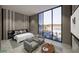 Staged primary bedroom featuring floor to ceiling windows, accent wall, neutral color palette, and seating area at 491 Cityview Ridge Dr, Henderson, NV 89012