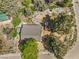 Aerial view of a house with a gray roof and surrounding yard, situated in a wooded area near a roadway at 3968 Mont Blanc Way, Las Vegas, NV 89124