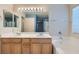 Bathroom featuring double sinks, large mirror, tub, and linen storage at 2731 Heathrow St, Las Vegas, NV 89135