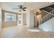 Bright living room showcasing tile floors, ceiling fan, and open access to the staircase and kitchen at 2731 Heathrow St, Las Vegas, NV 89135