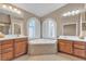 Stylish bathroom showcasing double vanities, soaking tub, and arched window at 11605 Cabo Del Sol Ct, Las Vegas, NV 89138