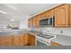 Bright kitchen featuring wooden cabinets, stainless steel microwave, and gas range at 7814 Ravenhollow Ln, Las Vegas, NV 89145