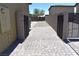 View of the backyard featuring block wall fence, gravel area with a small tree, and a stone paver path and patio at 7047 Noble Flair Ct, Las Vegas, NV 89131