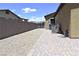 Side yard with gravel, brick pavers leading to a gated entrance, and a stucco wall at 7047 Noble Flair Ct, Las Vegas, NV 89131