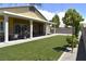 Covered patio overlooking a lush backyard with artificial turf, mature landscaping, and privacy at 7047 Noble Flair Ct, Las Vegas, NV 89131