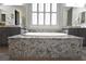 Bright bathroom featuring a soaking tub with granite surround and double sink vanity at 7047 Noble Flair Ct, Las Vegas, NV 89131
