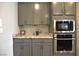 A modern kitchen with granite countertops, stainless steel appliances, and gray cabinets at 7047 Noble Flair Ct, Las Vegas, NV 89131